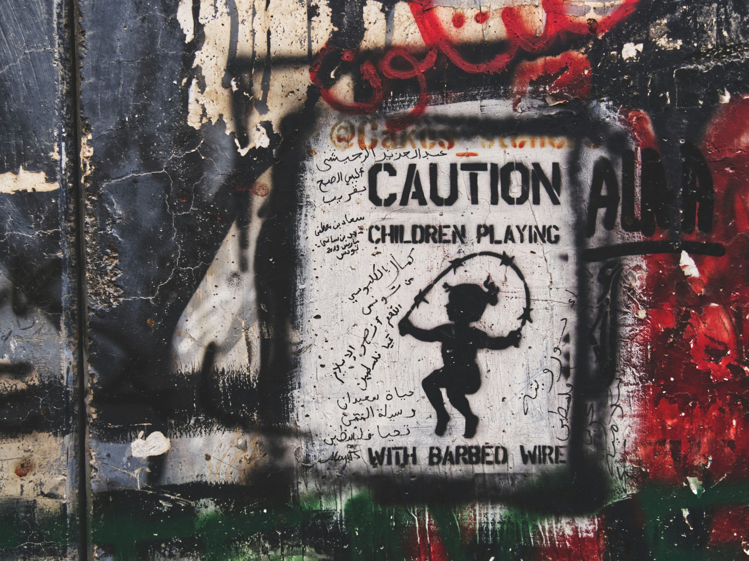 Spray painted sign reading CAUTION CHILDREN PLAYING WITH BARBED WIRE